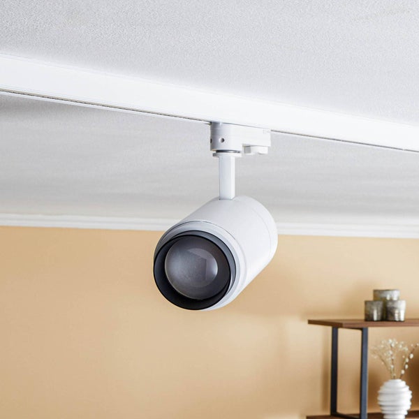 Zylindrischer Strahler für Schienensysteme, montiert an einer Deckenschiene in einem hellen Wohnraum.