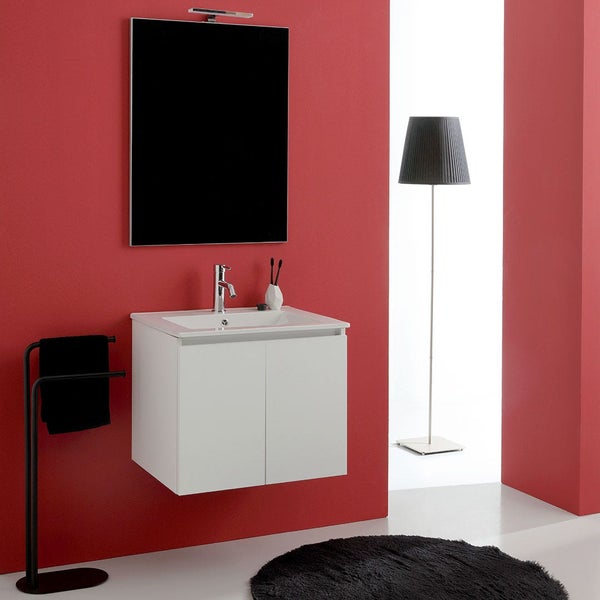Wandhängender Waschtischunterschrank mit integriertem Waschbecken, Spiegel mit Leuchte, Handtuchhalter und Stehlampe vor roter Wand.