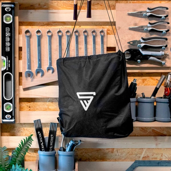 Werkstattwand mit Werkzeugen, Wasserwaage, Schraubenschlüsseln, Zangen und STAHLWERK Logo auf einer Tasche.