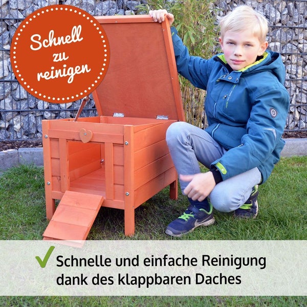 Kleintierhaus aus Holz mit aufklappbarem Dach für einfache Reinigung, Rampe und Herzverzierung auf Rasen im Garten.