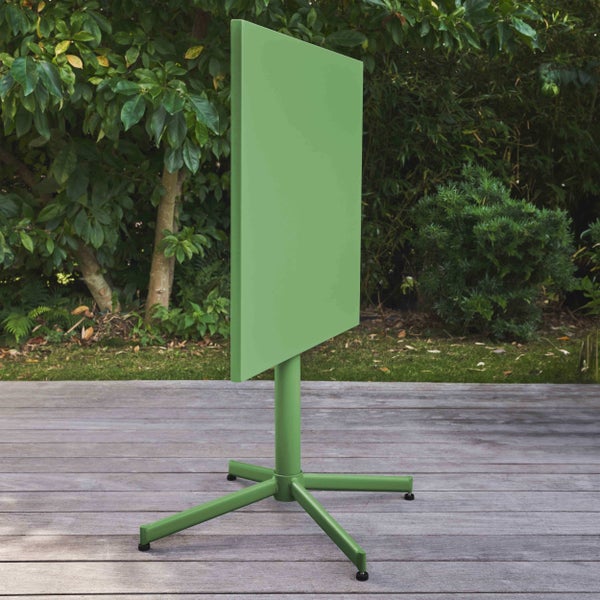 Grüner quadratischer Gartentisch mit hochgeklappter Tischplatte auf einer Holzterrasse vor Sträuchern.