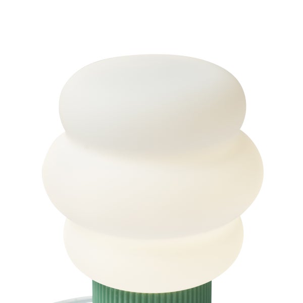 Moderne Tischleuchte mit weißem Glasschirm in dreistufiger abgerundeter Form und grünem geripptem Sockel.