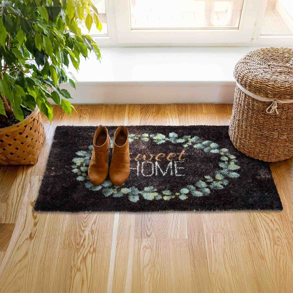 Fußmatte mit Schriftzug 'Sweet Home', Schuhen und Topfpflanze auf Holzboden