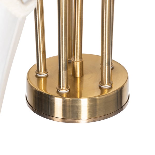 Nahaufnahme eines runden Lampenfußes mit mehreren vertikalen Metallstäben in goldfarbenem Design.