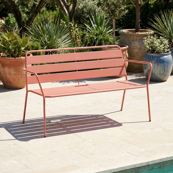 Moderne Gartenbank aus Metall mit Latten-Design auf einer hellen Terrasse mit verschiedenen Topfpflanzen.