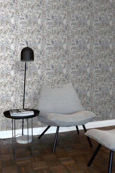 Wohnszene mit gemusterter Tapete, Sessel, Beistelltisch und Stehlampe.