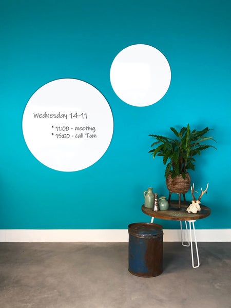 Zwei runde weiße Magnettafeln an einer Wand neben einem Beistelltisch mit Pflanze und Dekoration in einem modern gestalteten Raum.