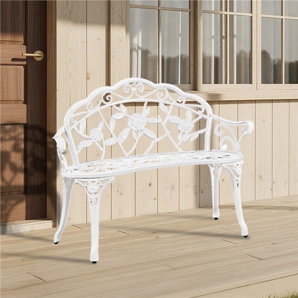 Weiße Gartenbank mit Rosenmuster vor Hauswand