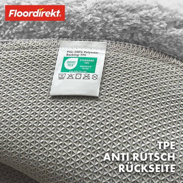 Detailansicht der Rückseite eines Teppichs mit Antirutschbeschichtung und Hinweisschild zur Materialzusammensetzung sowie dem Oeko-Tex Standard 100 Siegel.