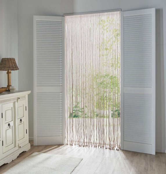 Dekorativer Fadenvorhang vor einem Fenster mit offenen Fensterläden.