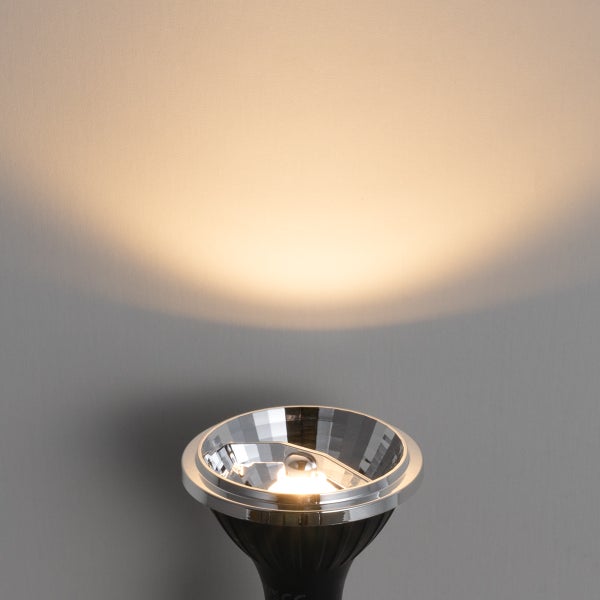 Eingeschaltetes LED-Reflektor-Leuchtmittel mit einem warmweißen Lichtkegel an einer Wand.