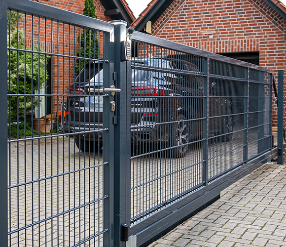 Schiebetor aus Metall mit Doppelstabmatten vor einem Haus