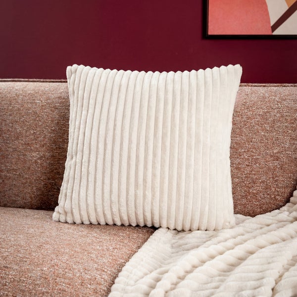 Dekoratives Cordkissen auf einem Sofa mit passender Decke