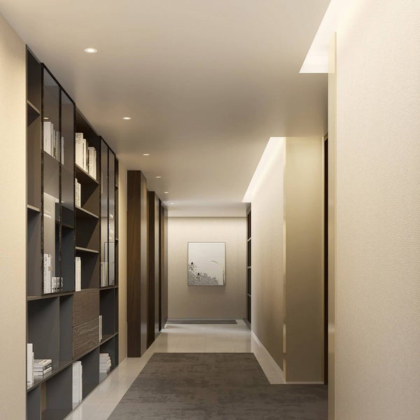 Moderner, heller Flur mit deckenhohem Bücherregal, Deckeneinbaustrahlern und dunkelgrauem Läufer. Ein Bild hängt am Ende des Ganges.