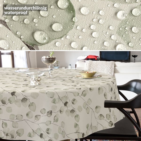 Wasserundurchlässige Tischdecke mit Blattmuster auf einem runden Tisch im Wohnzimmer. Detailaufnahme zeigt Wassertropfen auf der Oberfläche.