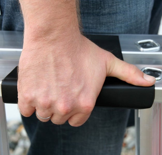 Hand eines Menschen beim Greifen des stabilen Tragegriffs einer Aluminiumleiter.
