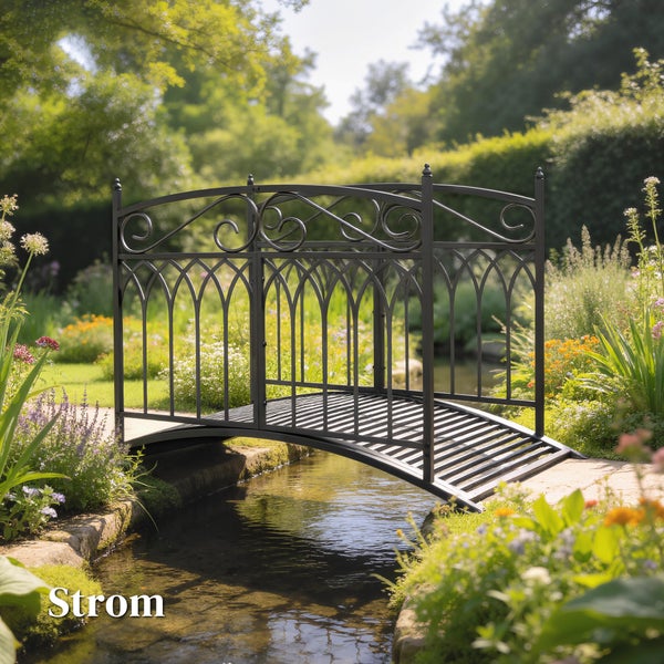 Filigrane Gartenbrücke aus Metall mit gotischen Bögen und Schnörkeln über einem Bachlauf in einem hellen, organisierten Garten.