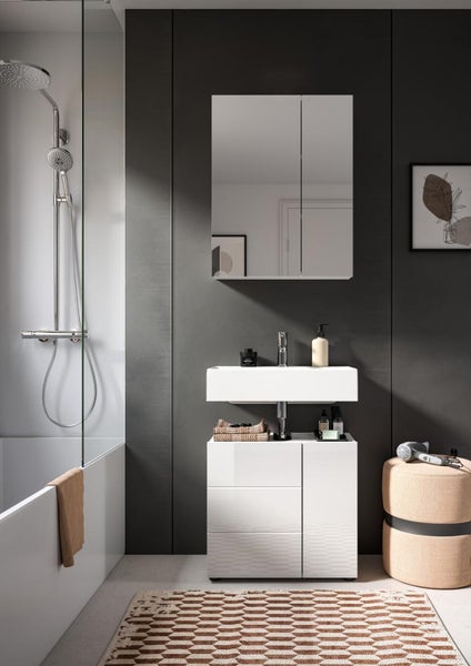 Modernes Badezimmer mit weißem Waschtisch, passendem Unterschrank, Spiegelschrank und Duscharmatur vor dunkelgrauer Wand.