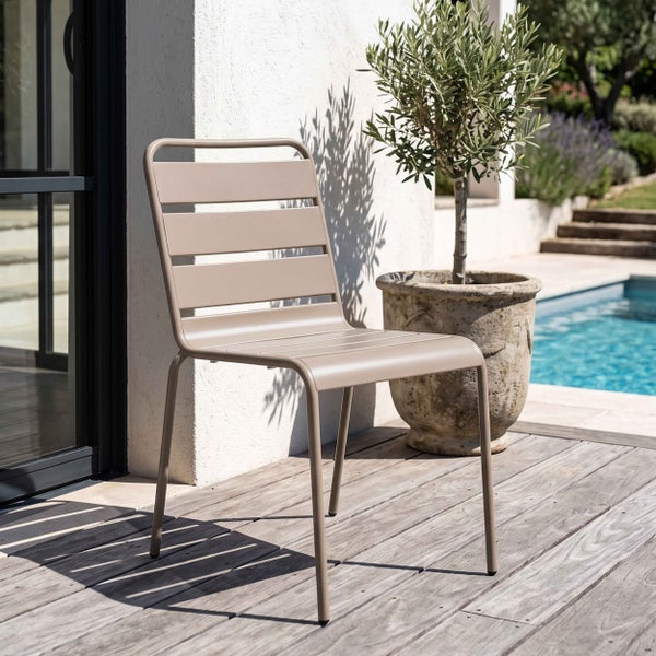 Moderner Gartenstuhl aus Metall mit Querstreben auf einer Holzterrasse neben einem Olivenbaum im Topf und einem Swimmingpool.