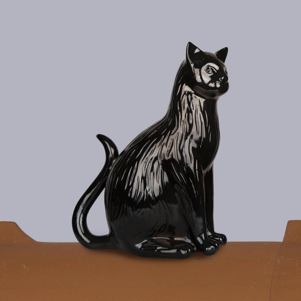 Schwarze Firstfigur Katze aus glasierter Keramik auf einem braunen Firstziegel sitzend.