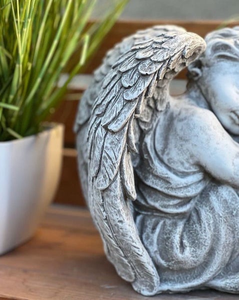 Nahaufnahme einer dekorativen Engel-Steinfigur mit detailreichen Flügeln, geeignet für Garten- oder Grabdekoration.