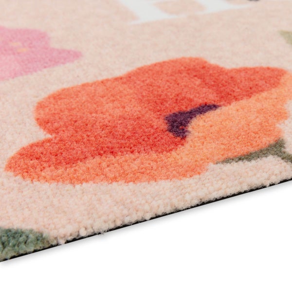 Nahaufnahme einer beigen Fußmatte mit Blumenmuster, weicher Flor-Struktur und rutschfester Unterseite.