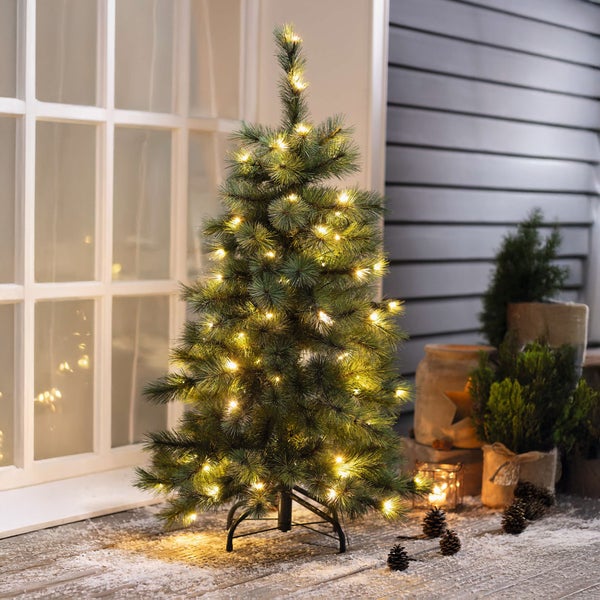 Geschmückter künstlicher Weihnachtsbaum mit Beleuchtung auf einer Terrasse.