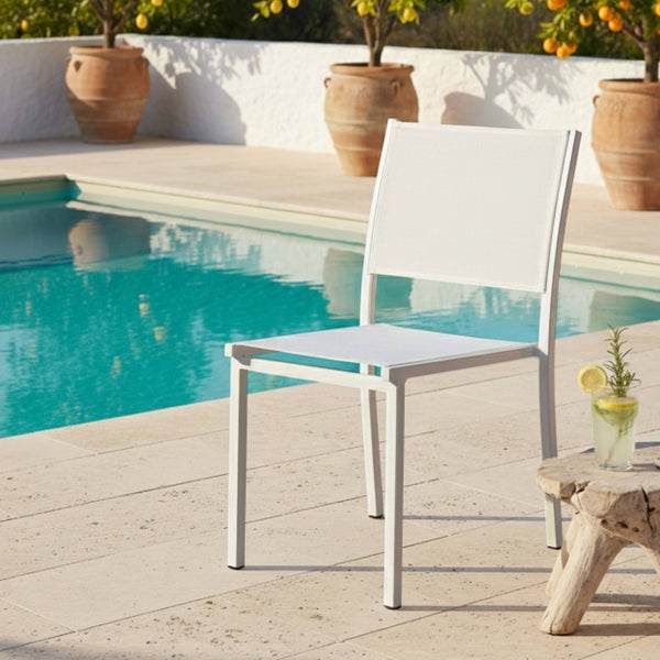 Ein weißer Gartenstuhl aus Metall und Stoff steht auf einer Steinterrasse neben einem Swimmingpool.