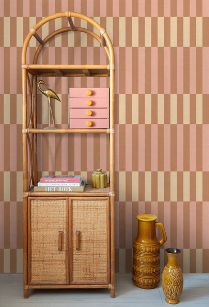 Tapete mit geometrischem Streifenmuster in einem Wohnbereich mit einem Rattanregal und Keramikvasen.
