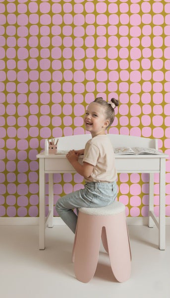 Vliestapete mit rosa geometrischem Retro-Muster im Kinderzimmer mit weißem Schreibtisch und Kind.