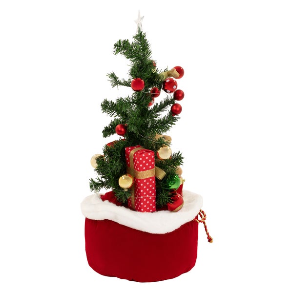 Geschmückter künstlicher Weihnachtsbaum in einem weihnachtlichen Jutesack mit Geschenken und Christbaumkugeln.