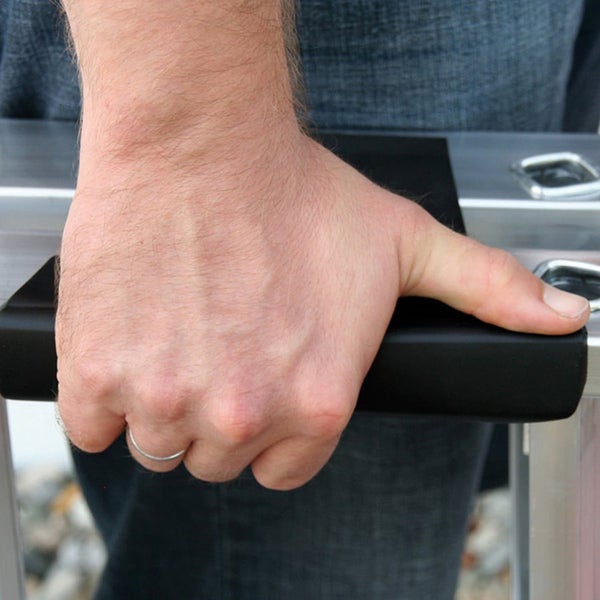 Eine Hand greift den schwarzen Holm einer Aluminiumleiter.