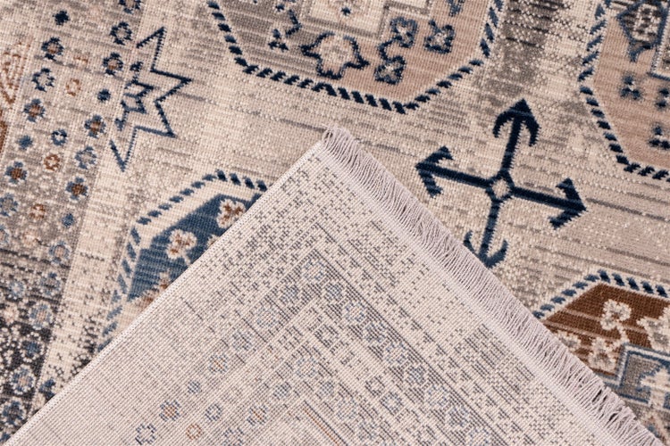 Nahaufnahme eines Teppichs mit traditionellem orientalischem Muster, geometrischen Motiven und Fransen. Eine Ecke ist umgeklappt.