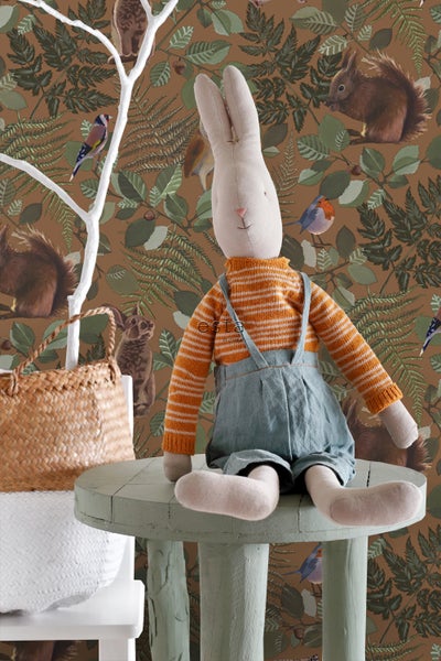 Dekorative Szene mit Stoffhase auf Tisch und Tapete mit Waldmotiven