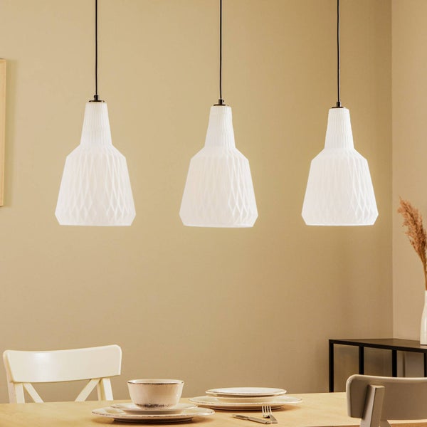 Drei weiße Pendelleuchten mit geometrischer Struktur über einem Holztisch in einem hellen Esszimmer.