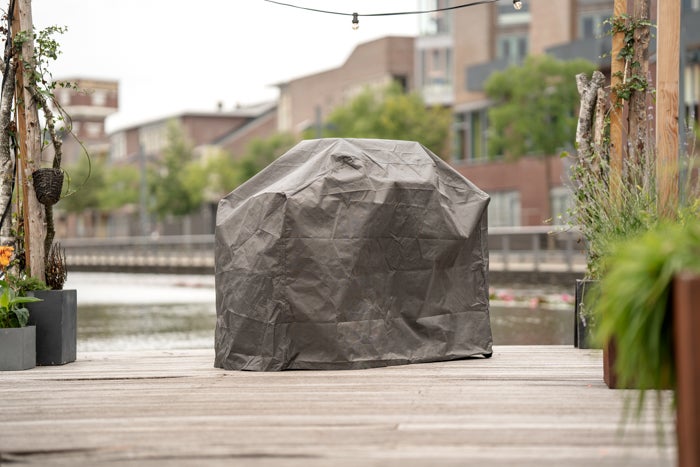 Grill mit Schutzhülle auf Holzterrasse