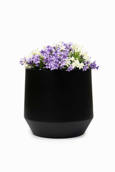Schwarzer matter Pflanztopf mit violetten und weißen Kunstblumen.