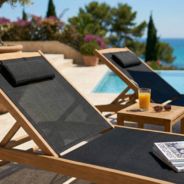 Sonnenliegen aus Holz mit schwarzem Textilgewebe an einem Pool mit Beistelltisch aus Holz.