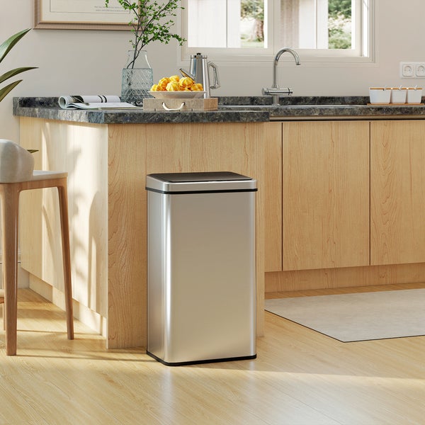 Rechteckiger Abfalleimer aus Edelstahl mit schwarzem Deckel in einer modernen, hellen Küche mit Holzschränken und hellem Holzboden.