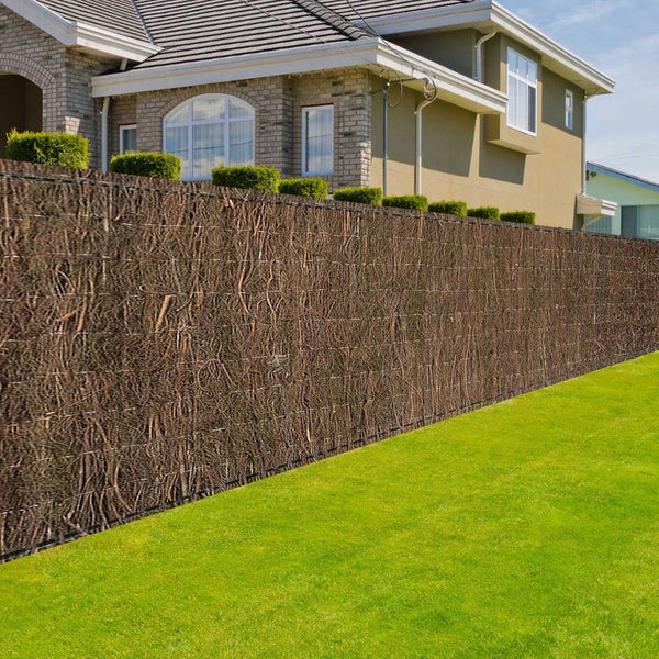 Gartenszene mit einem Zaun aus natürlichen Zweigen für Sichtschutz und Dekoration.
