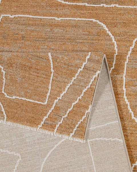 Nahaufnahme eines strukturierten braunen Teppichs mit weißem geometrischem Muster und einer umgeklappten Ecke, die die Rückseite zeigt.