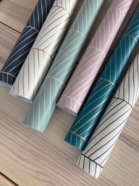 Verschiedene Rollen Tapeten mit geometrischem Muster auf einem Holztisch