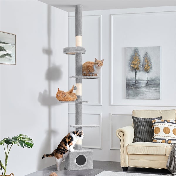 Katzenkratzbaum mit mehreren Ebenen und drei Katzen in einem hellen Wohnzimmer.