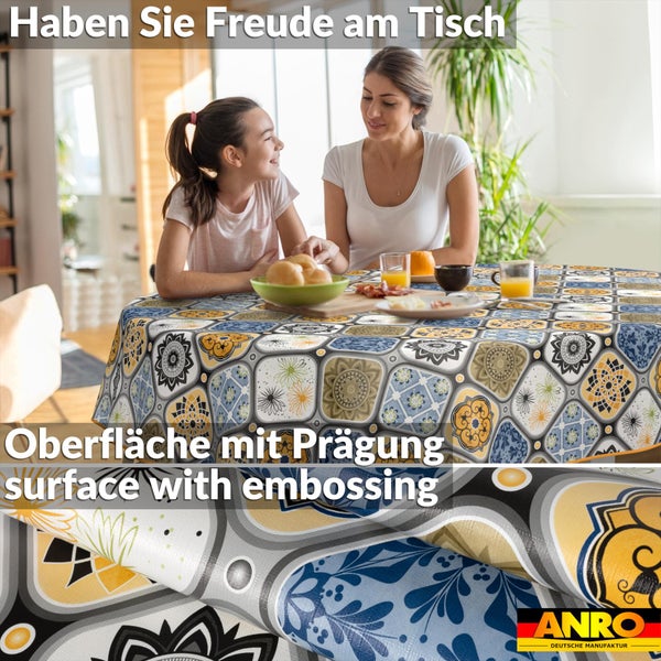 Helle Wohnraumszene mit rundem Tischtuch mit ornamentalem Kachelmuster und geprägter Oberfläche. Frau und Kind am gedeckten Tisch. Anro Logo.