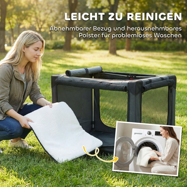 Eine Frau nimmt das weiße, waschbare Polster aus einer faltbaren Hundetransportbox auf einer Wiese in einer hellen Außenszene.