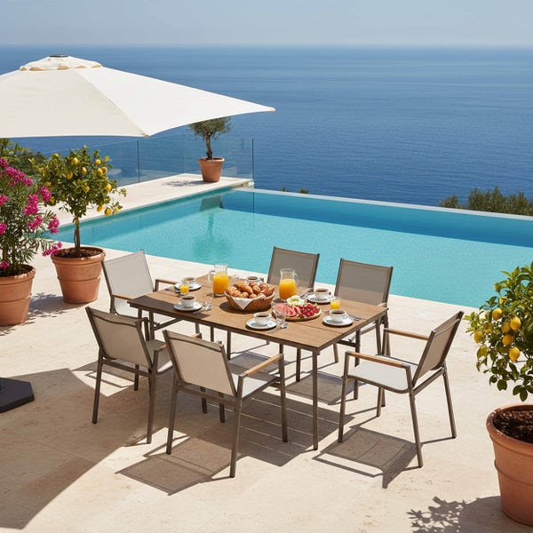 Gartenmöbel-Set bestehend aus einem Esstisch aus Holz und sechs Gartenstühlen auf einer sonnigen Terrasse mit Pool und Meerblick.
