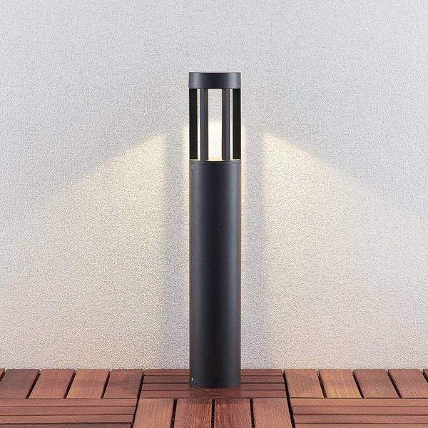 Zylindrische Außenleuchte in Anthrazit mit warmem Licht aus vertikalen Öffnungen oben, auf einer Holzterrasse.