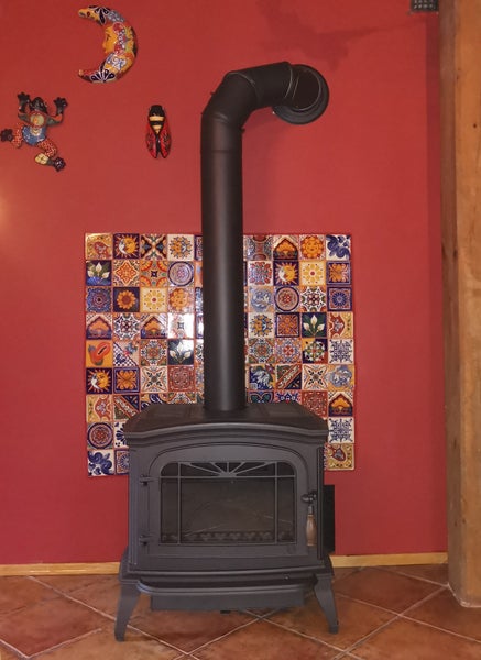 Küchenansicht mit weißen Schränken, Dunstabzugshaube und Mosaikfliesen