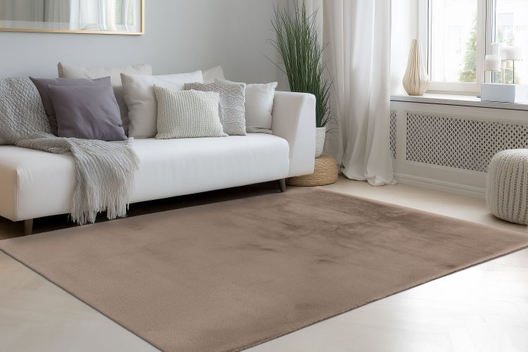 Ein unifarbener Wohnzimmerteppich in einem hellen Wohnzimmer mit Sofa und dekorativen Kissen.