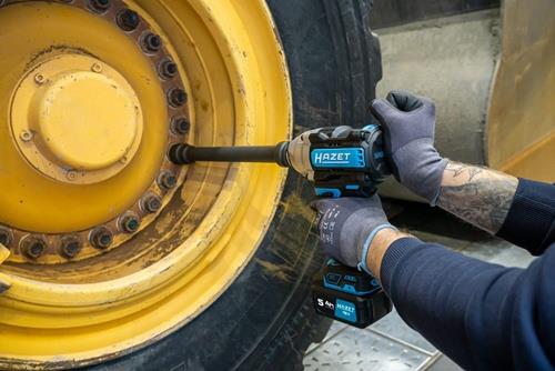 Ein Hazet Akku-Schlagschrauber wird verwendet, um die Radmuttern eines gelben, großen Rades festzuziehen.